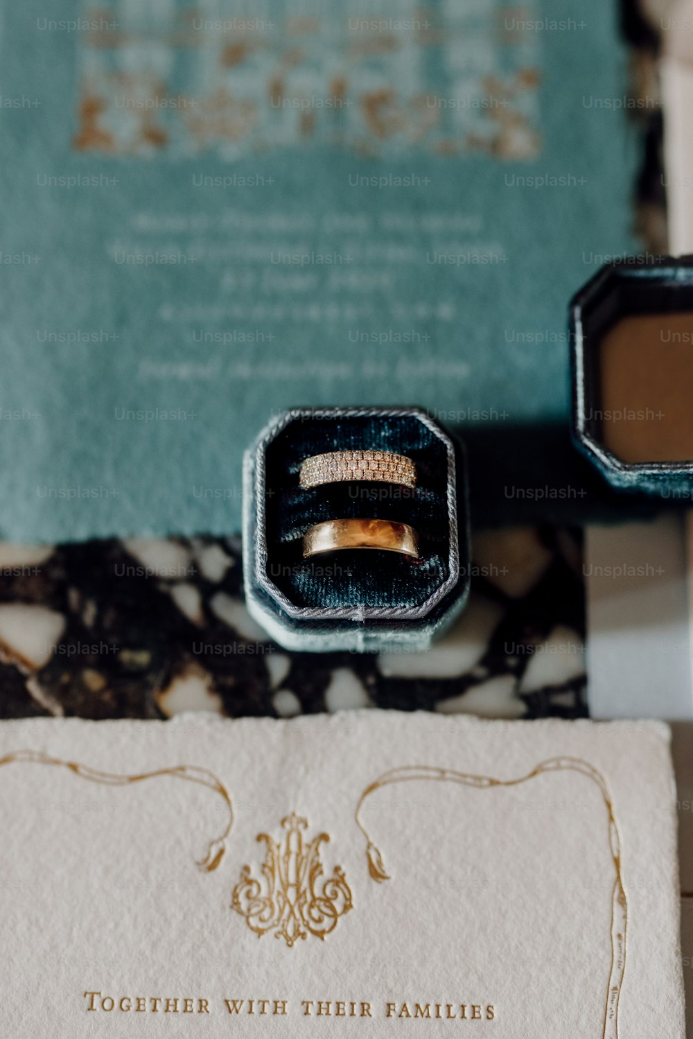 a wedding ring sits in a box next to a letter