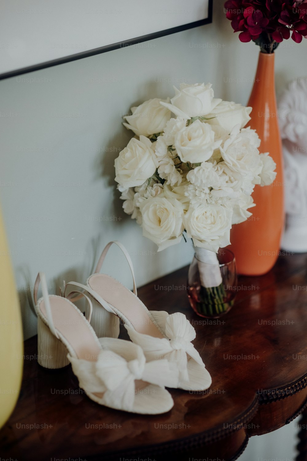 um par de sapatos brancos sentados em uma mesa ao lado de um vaso de flores
