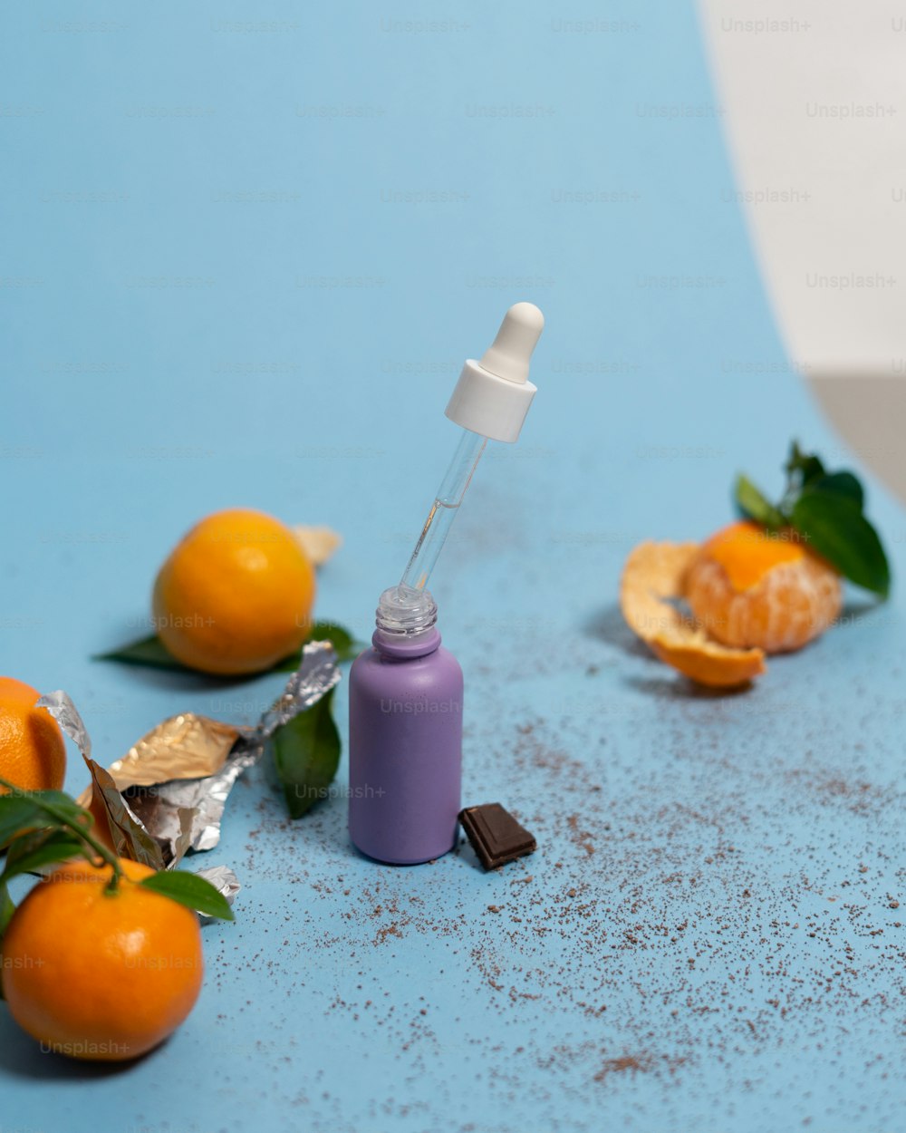 a bottle of liquid sitting on top of a table next to oranges