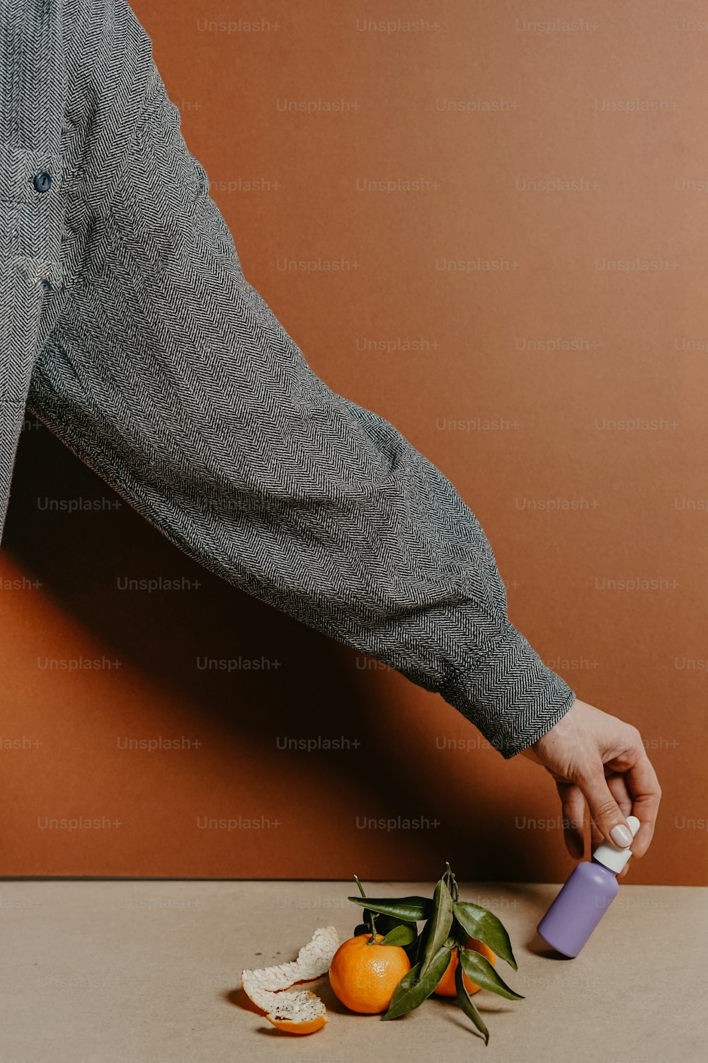 a person is holding a bottle over a pile of fruit