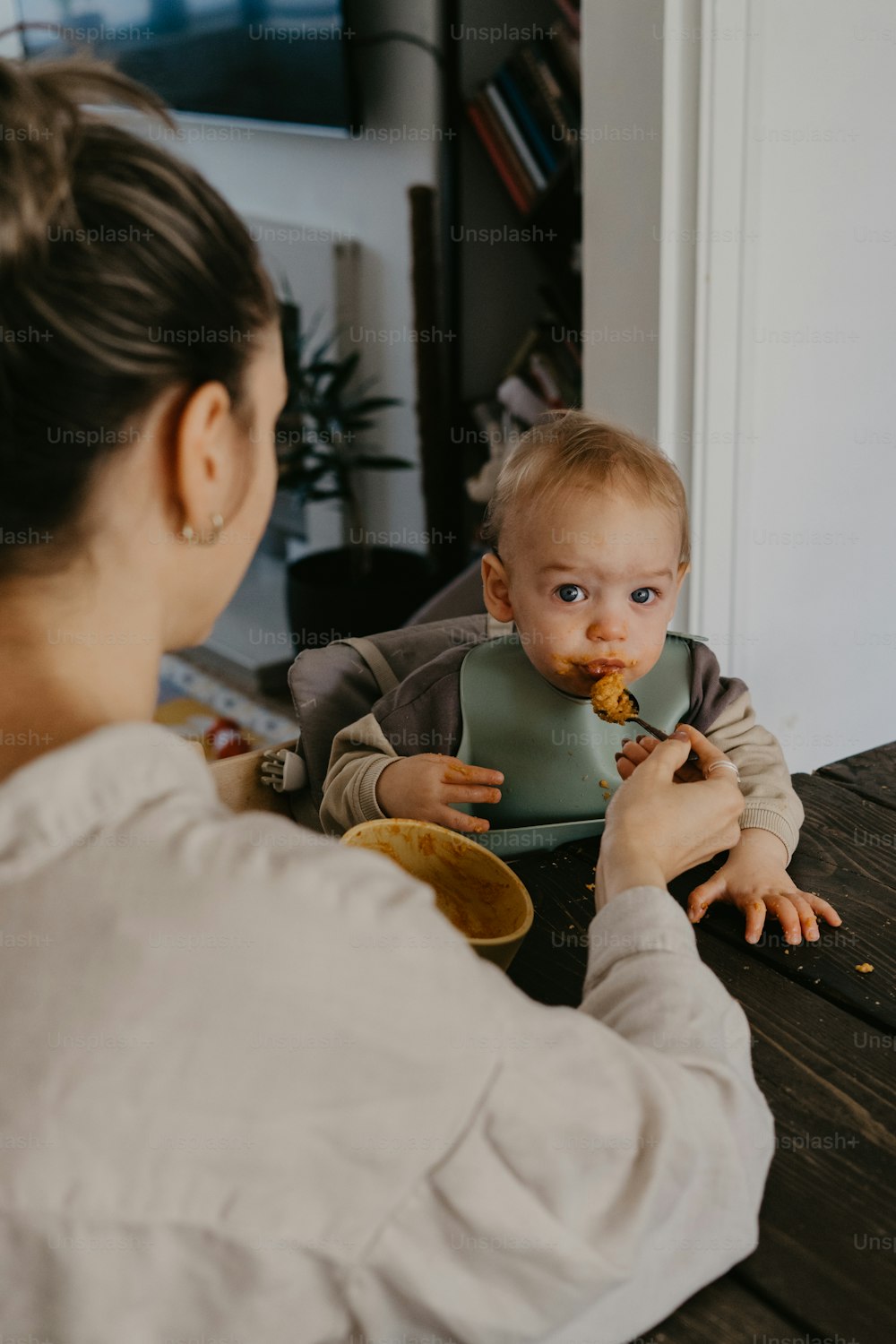 a woman feeding a baby with a spoon