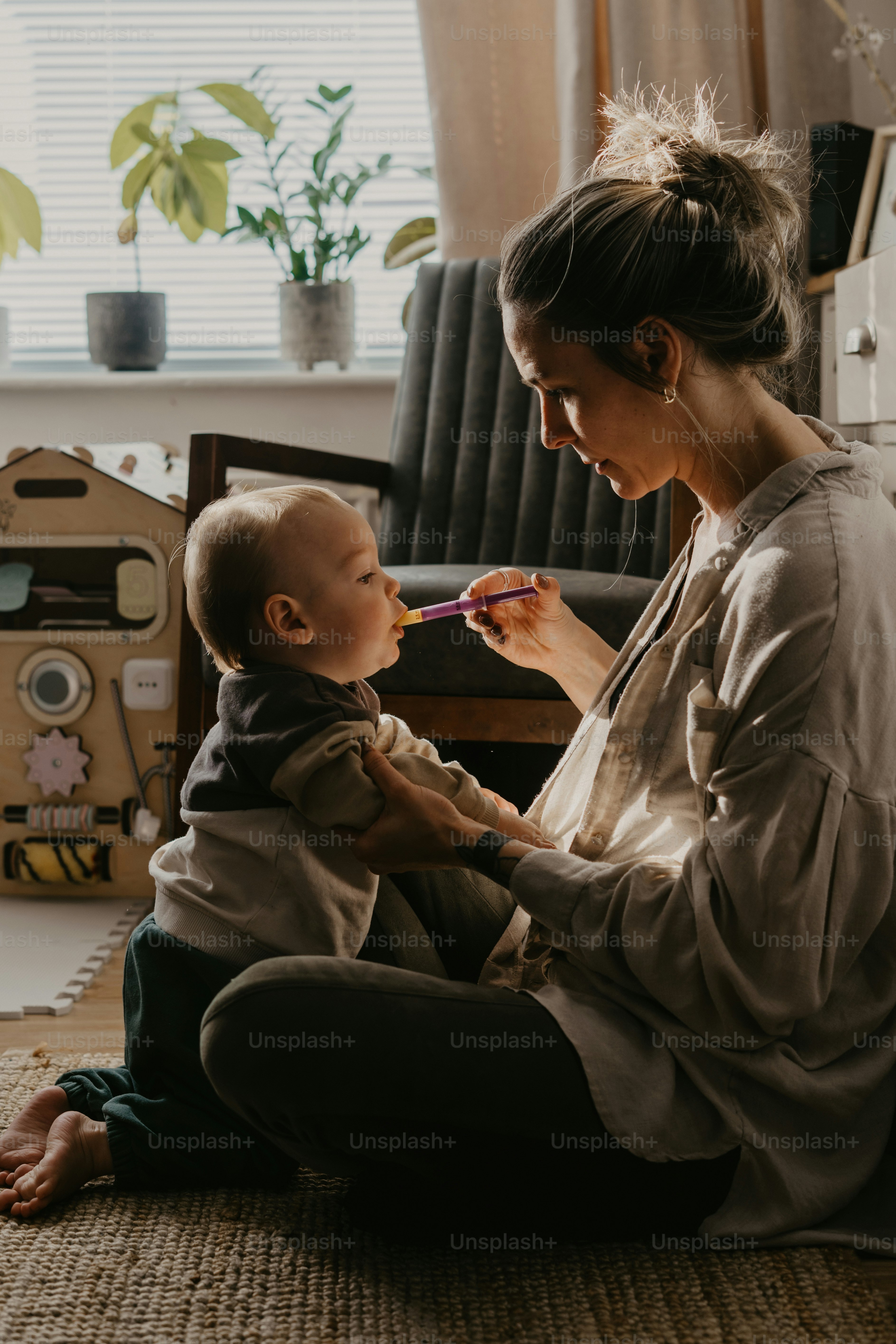 Una mujer sentada en el suelo cepillando los dientes de un bebé