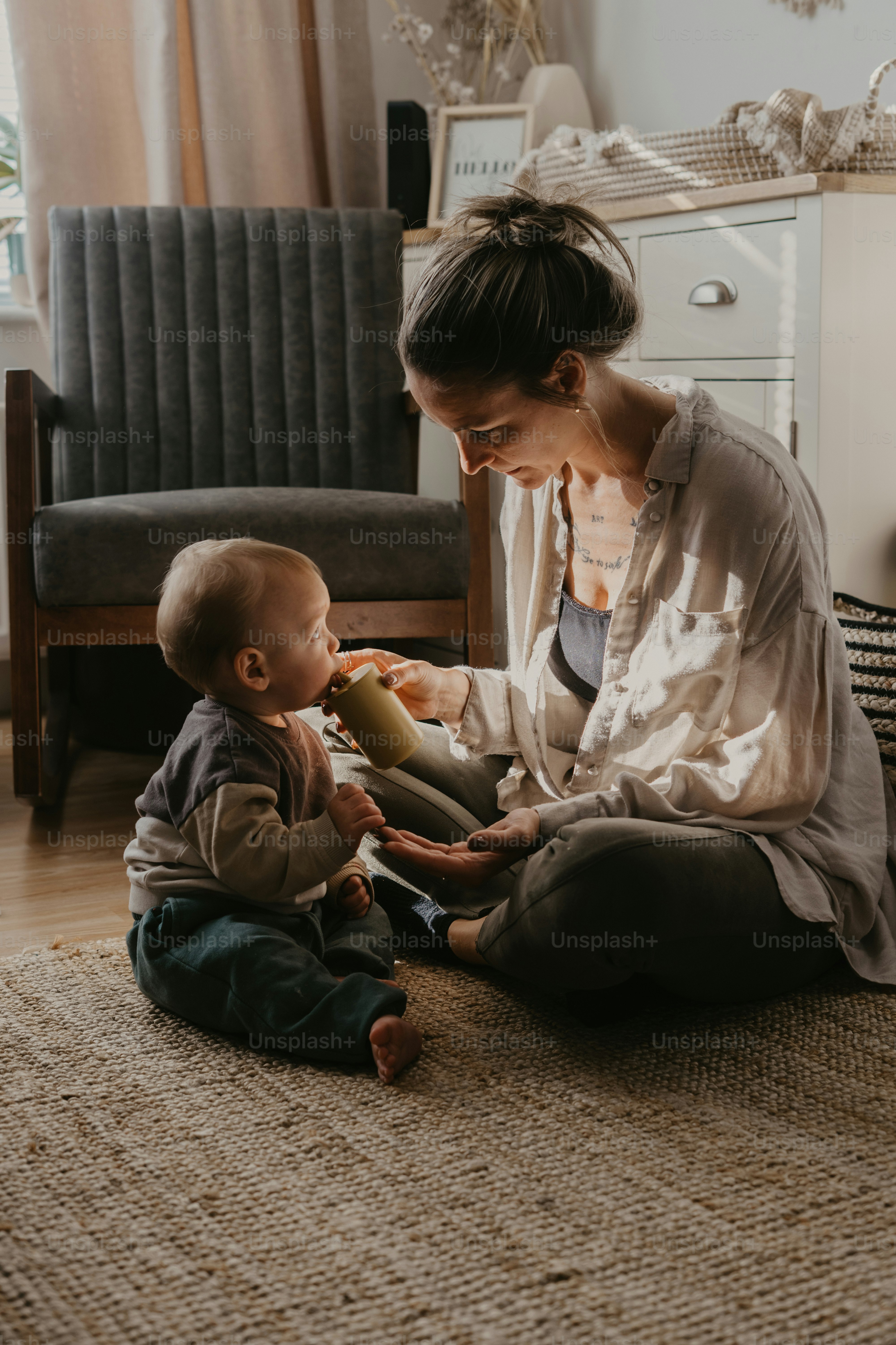 a woman sitting on the floor playing with a baby