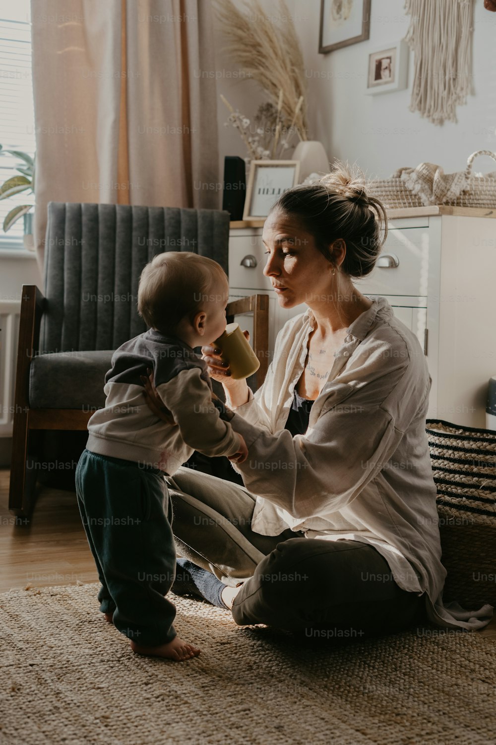 a woman sitting on the floor playing with a baby