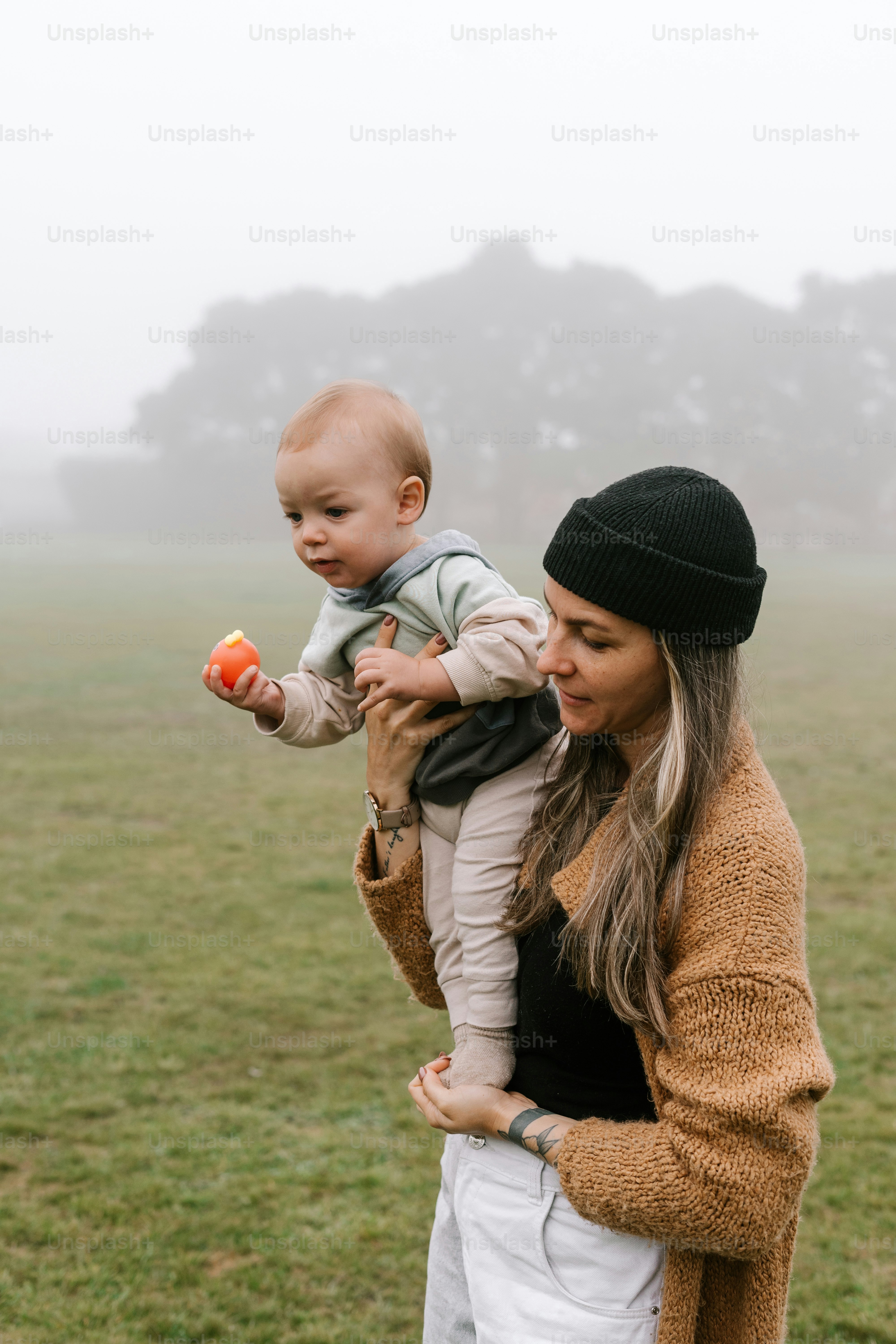 a woman holding a baby in a field