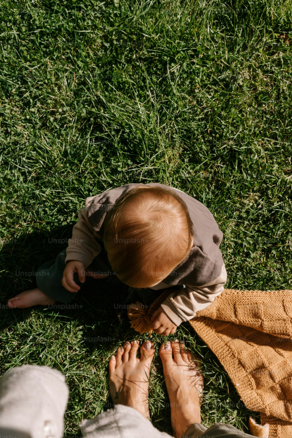 풀밭에 담요를 깔고 앉아 있는 아기