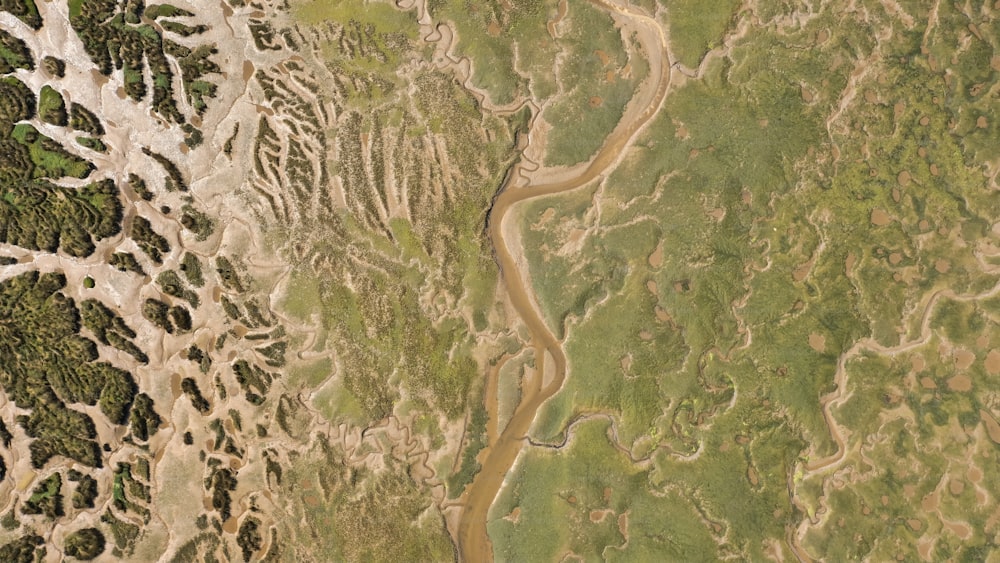 an aerial view of a river running through a lush green field