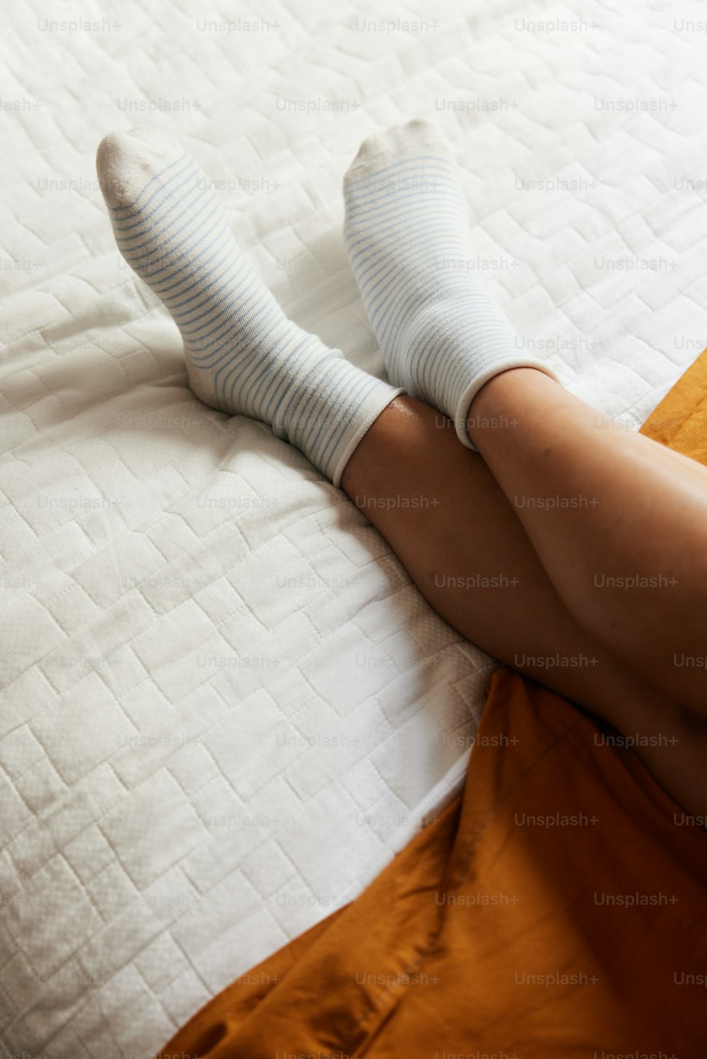 a person laying on a bed with white socks