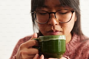 a woman in glasses holding a green cup