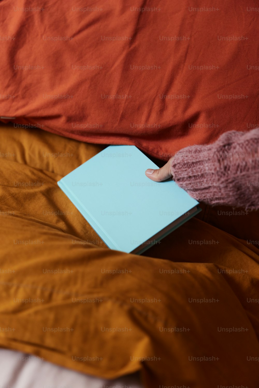 a person holding a book on a bed