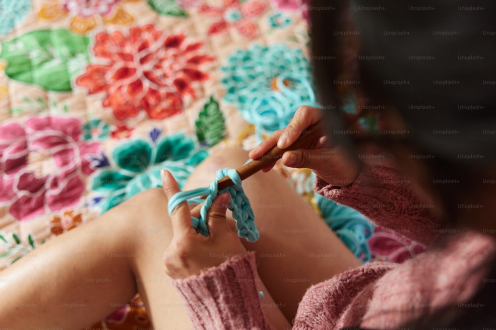a woman knitting a piece of fabric with a crochet hook
