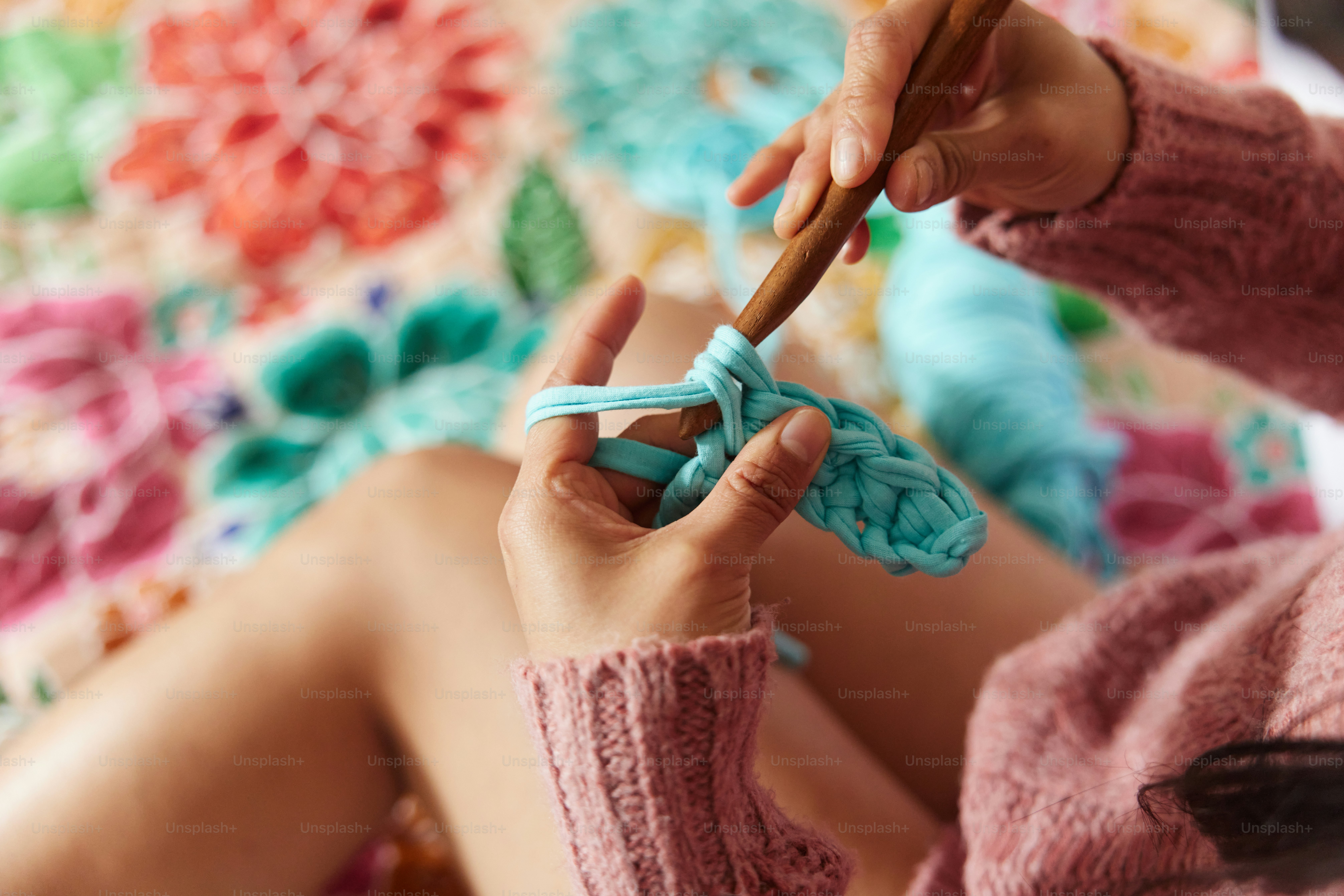 a woman sitting on a bed holding a crochet hook