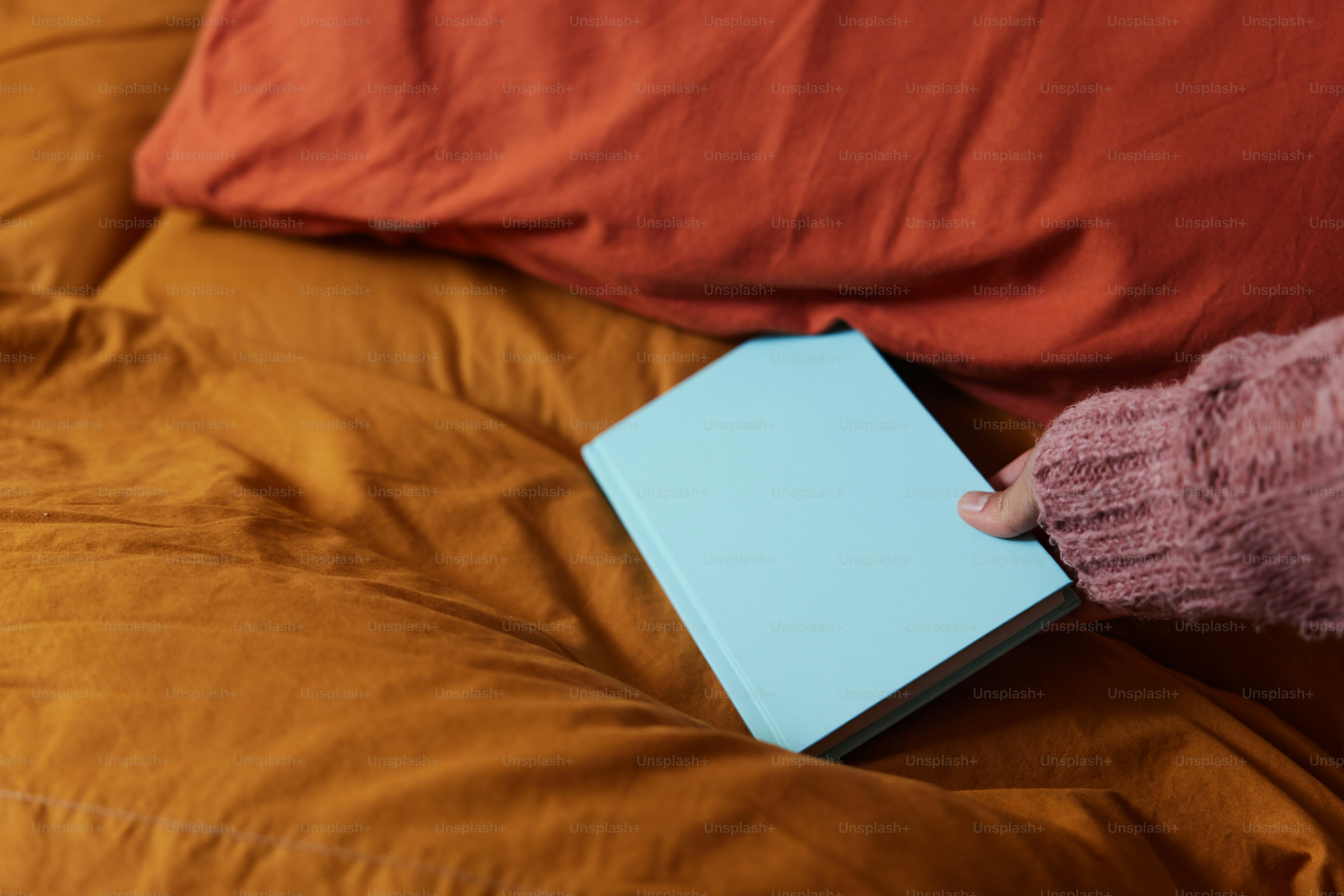 a person holding a book on a bed