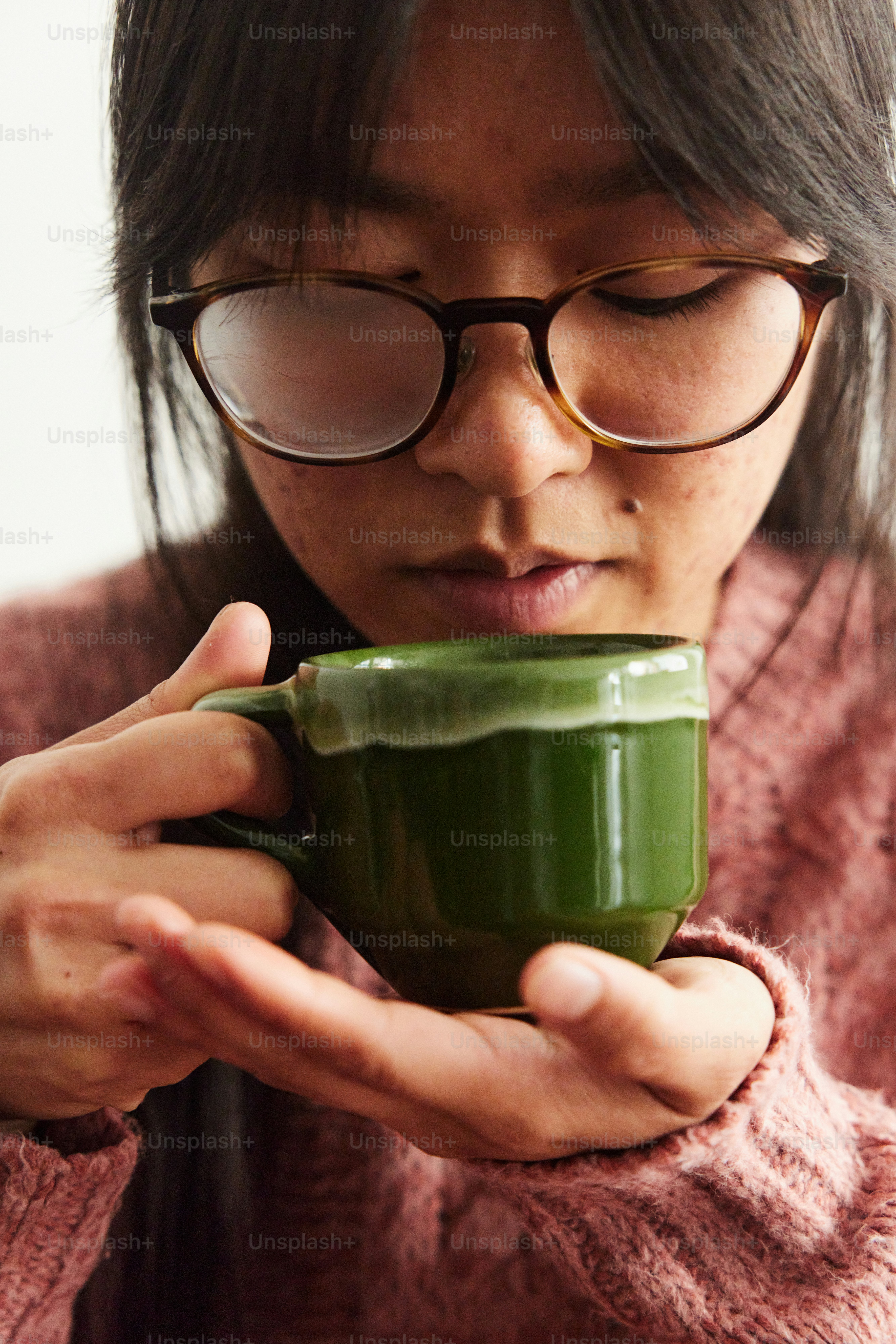Una donna che porta gli occhiali che tiene una tazza verde