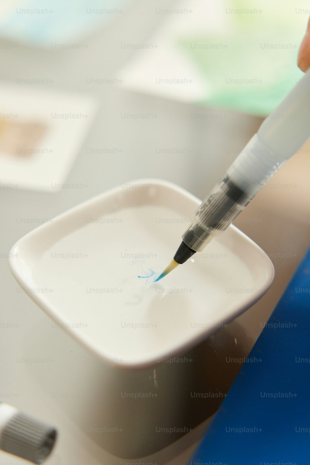 a person holding a pen in a white container