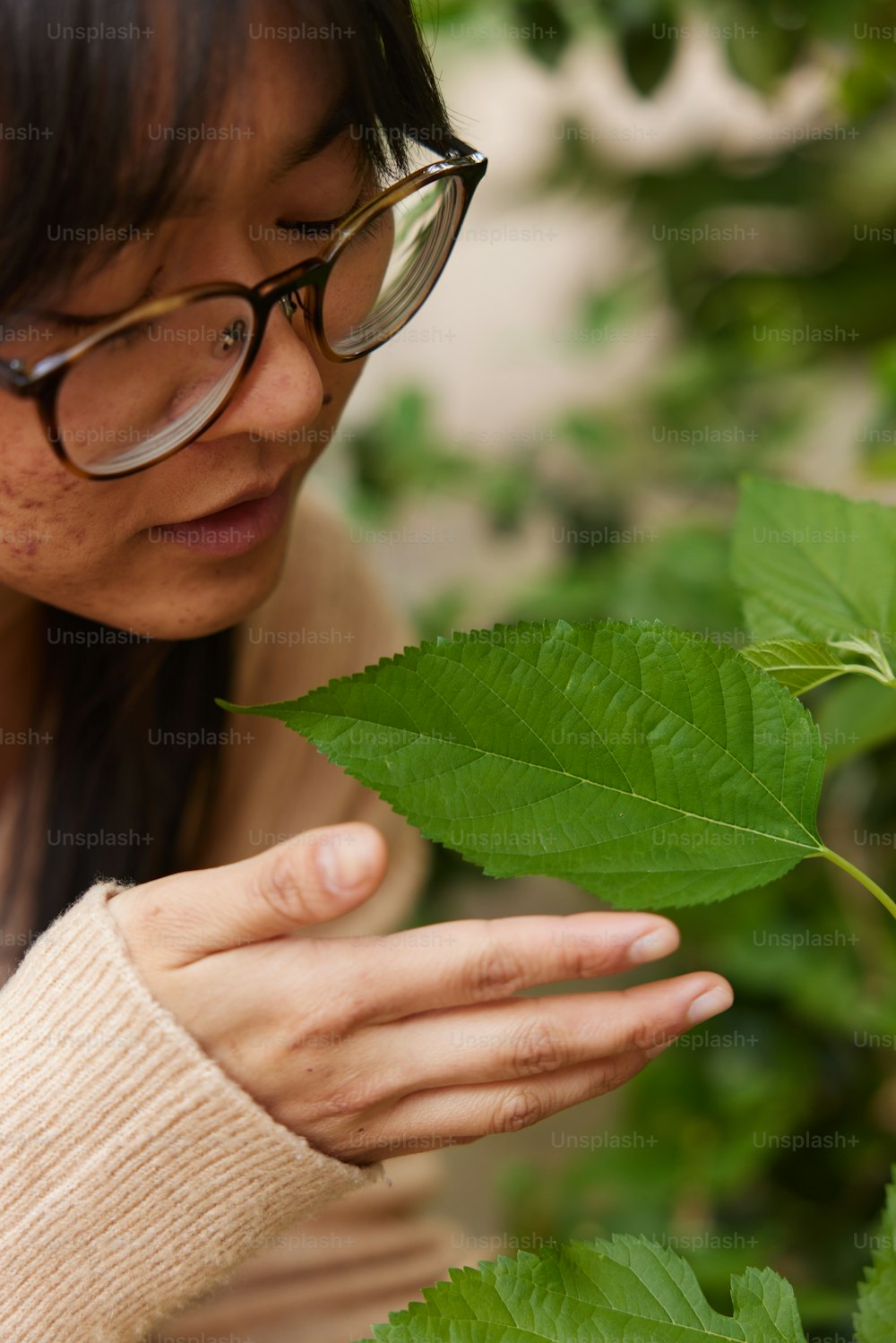a woman wearing glasses looking at a leaf