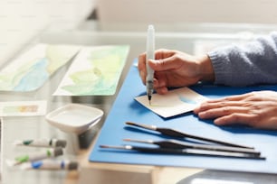 a person holding a pen and writing on a piece of paper