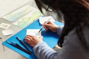 a woman sitting at a table working on a piece of paper