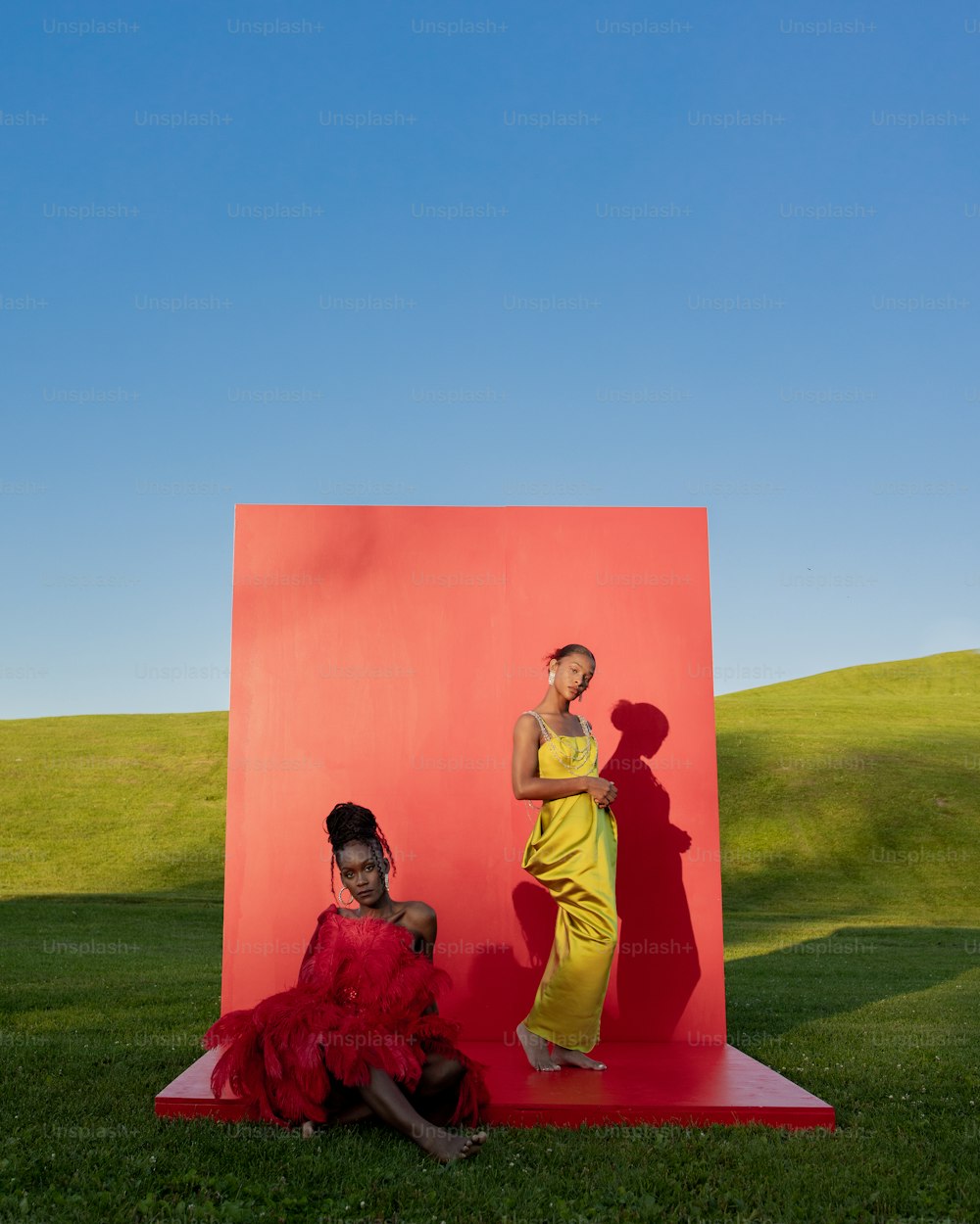 Una mujer con un vestido amarillo sentada junto a una mujer con un vestido rojo