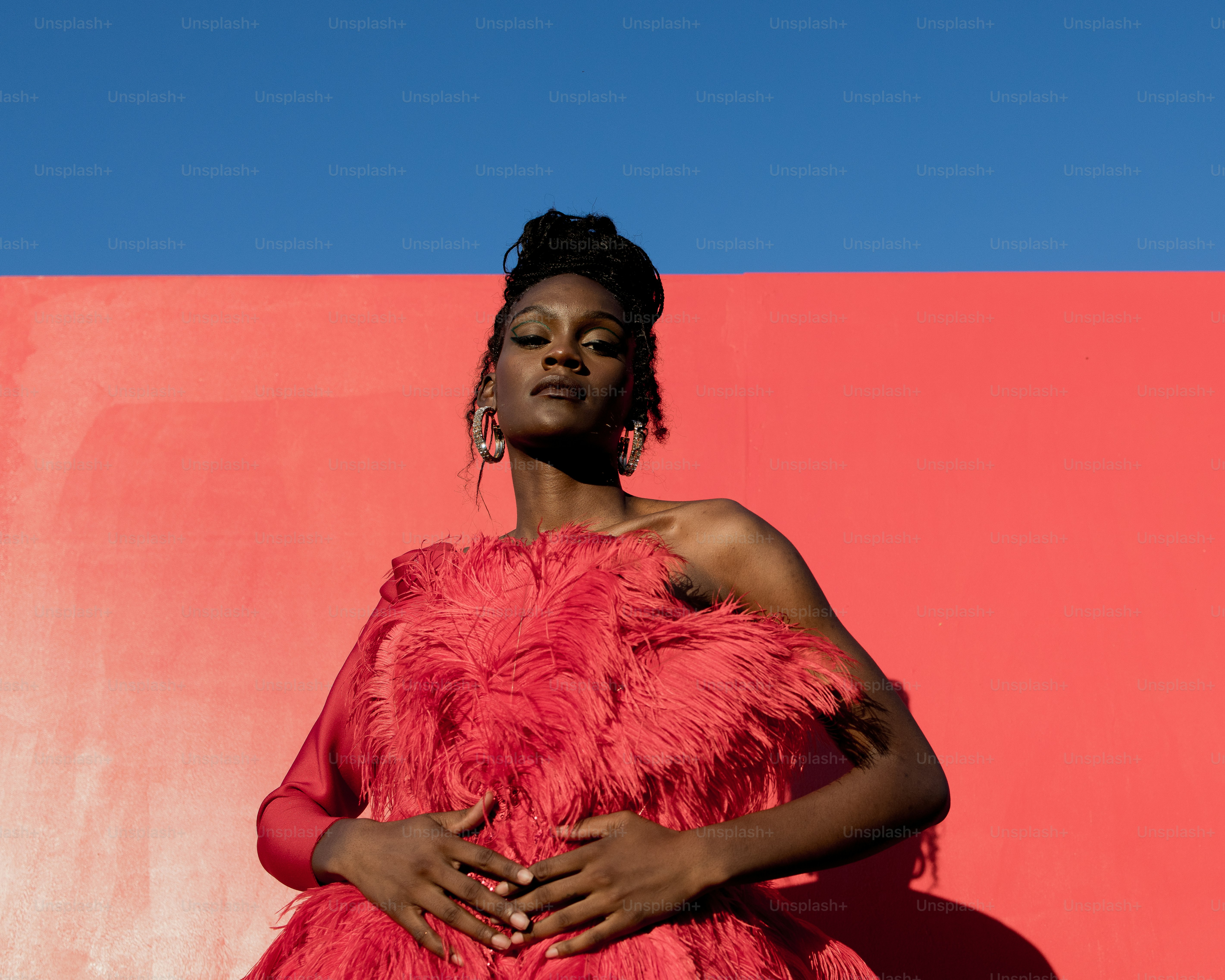a woman in a pink dress standing in front of a pink wall