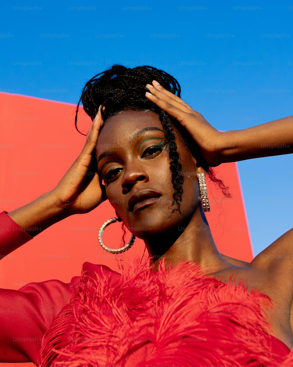 a woman in a red dress with her hands on her head