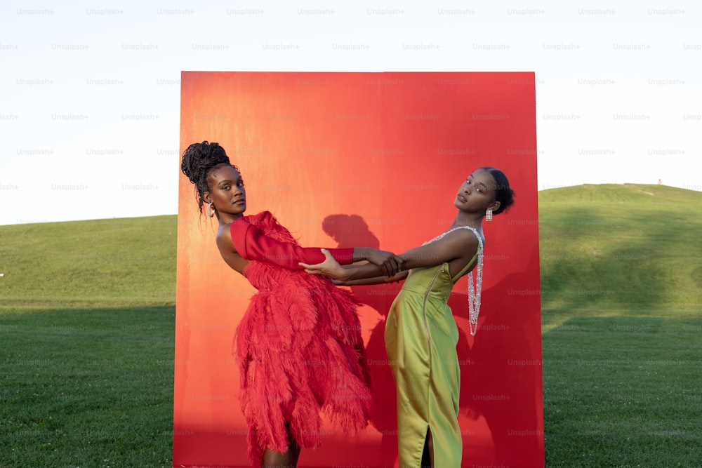 two women standing in front of a red sculpture