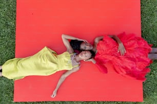 풀밭에 빨간 매트를 깔고 누워 있는 두 소녀