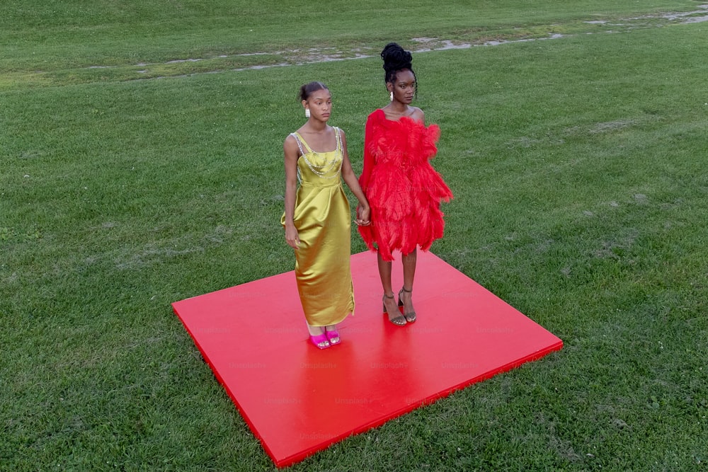 two women standing on a red mat in a field