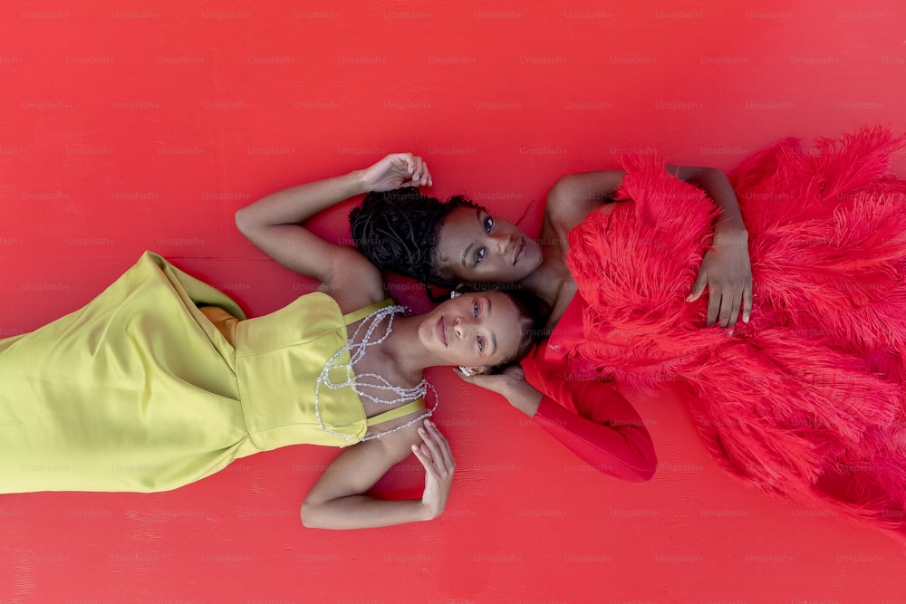 two women in dresses laying on the ground