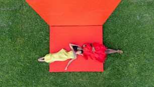 a couple of women laying on top of a red object