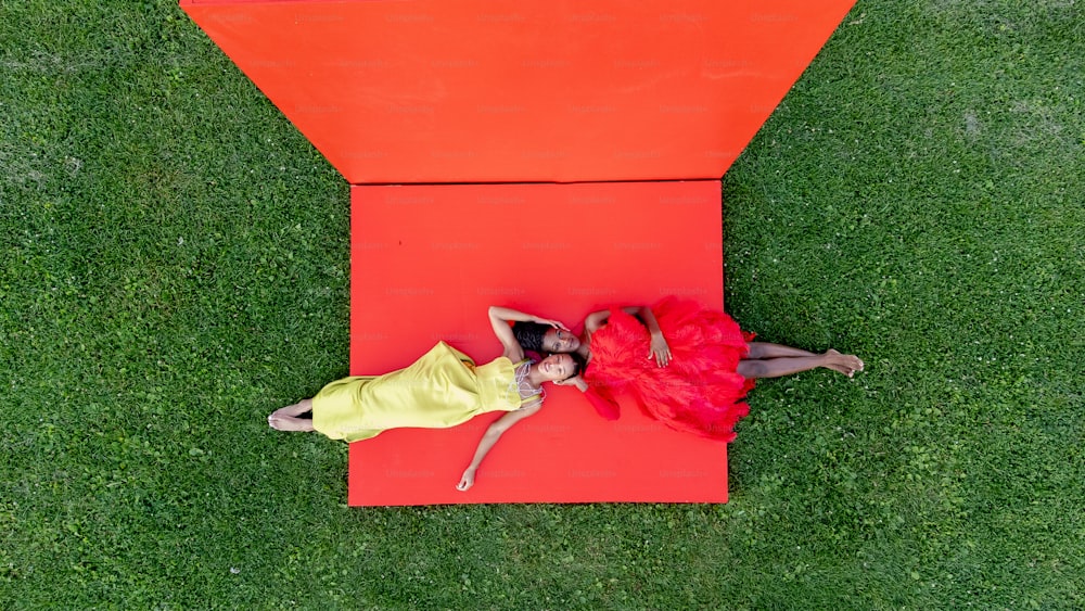 a couple of women laying on top of a red object