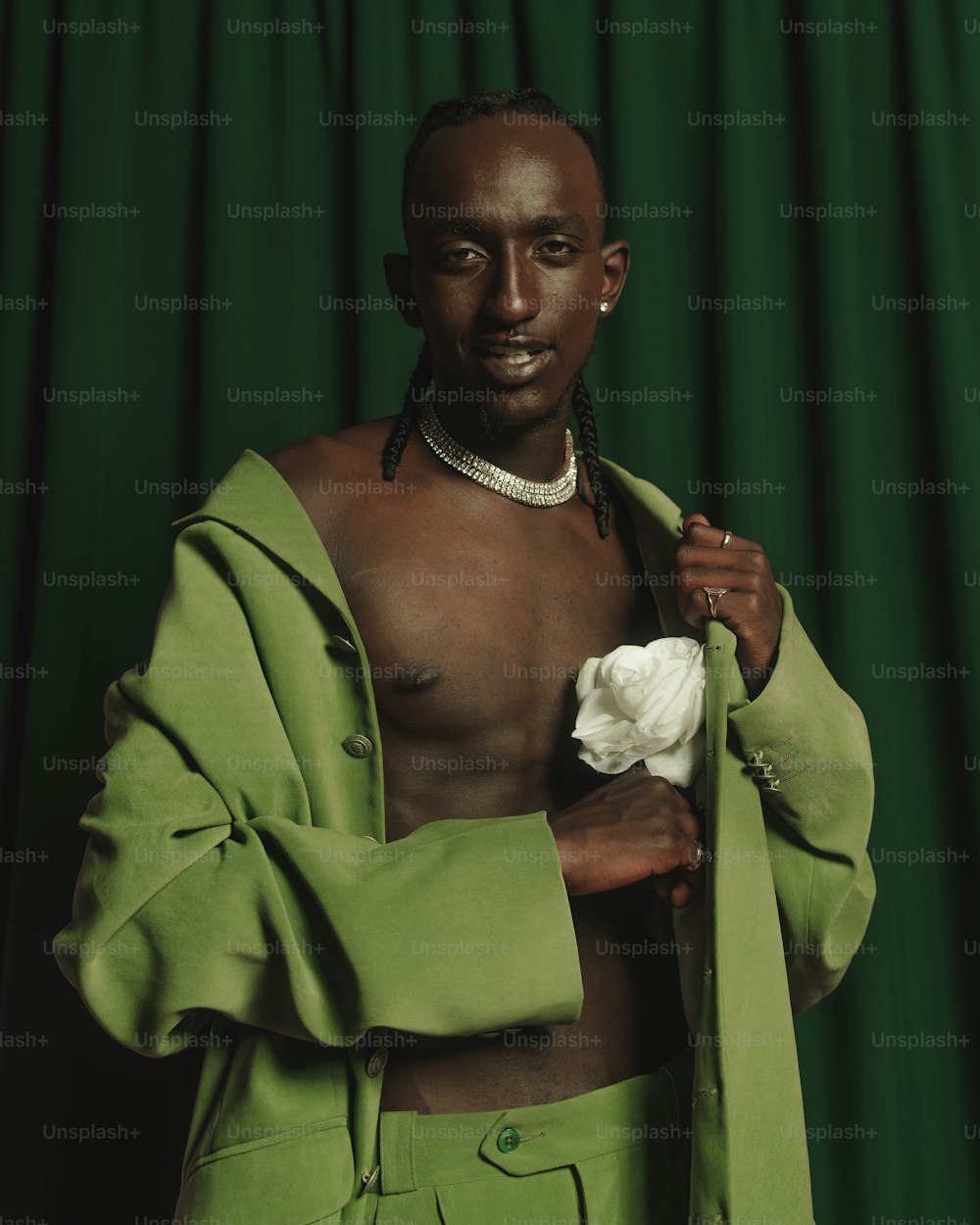 Un hombre con un traje verde sosteniendo una flor blanca