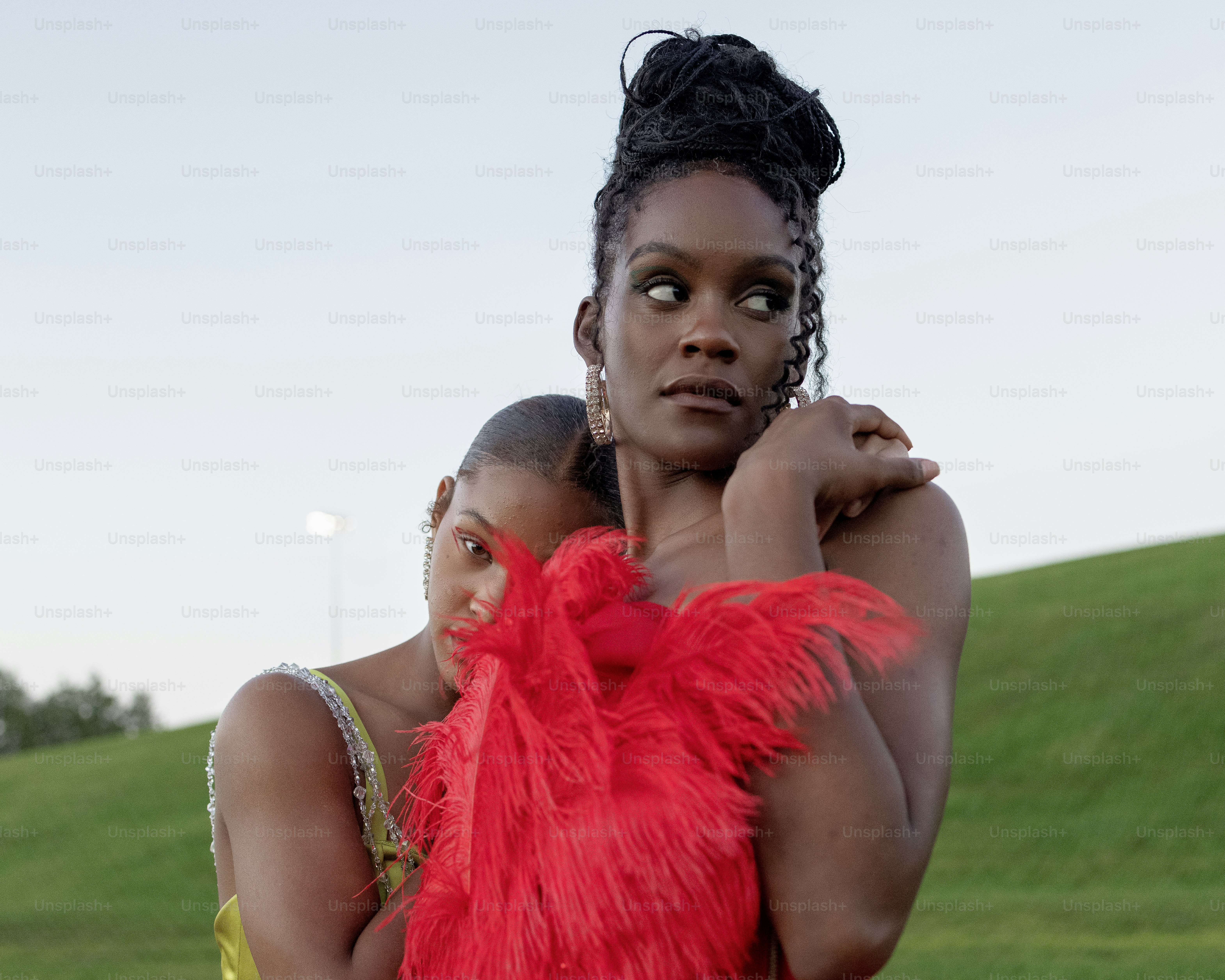 une femme en robe rouge à plumes debout à côté d’une femme en jaune