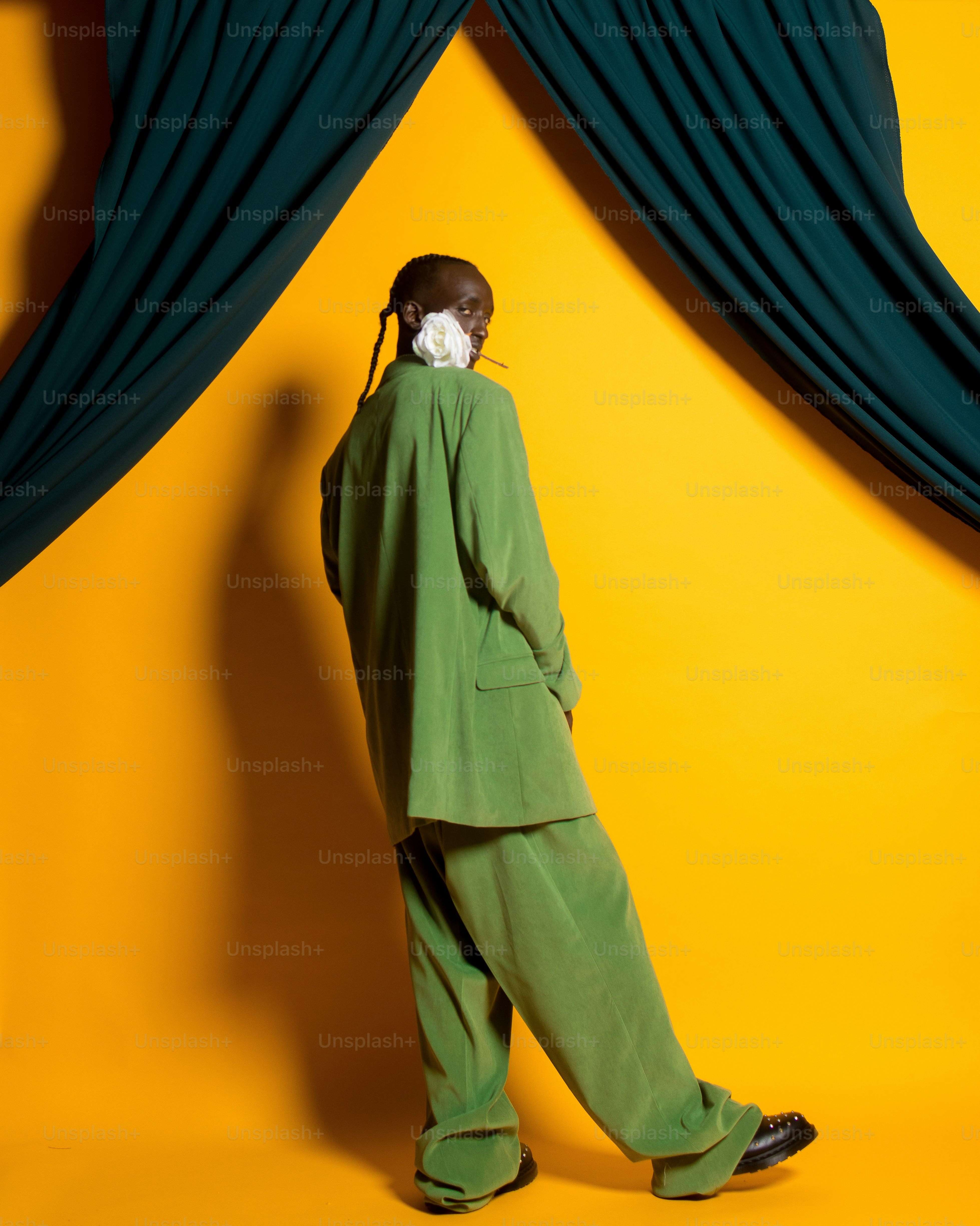 a man in a green suit standing in front of a yellow wall