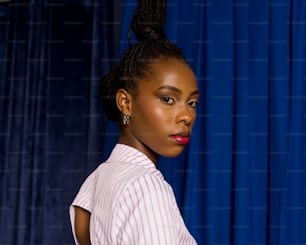 a woman with a ponytail standing in front of a blue curtain