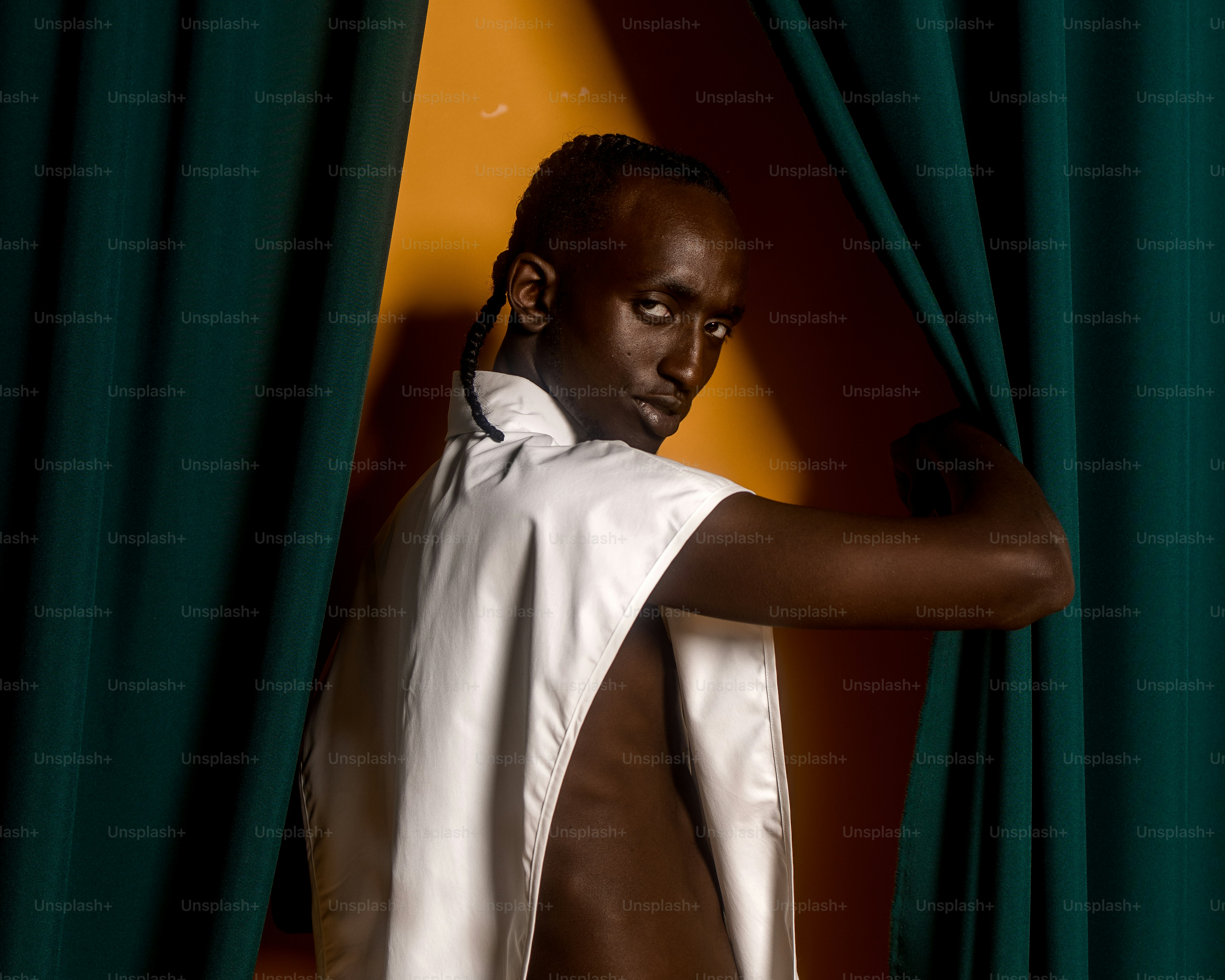 a man in a white shirt and a green curtain