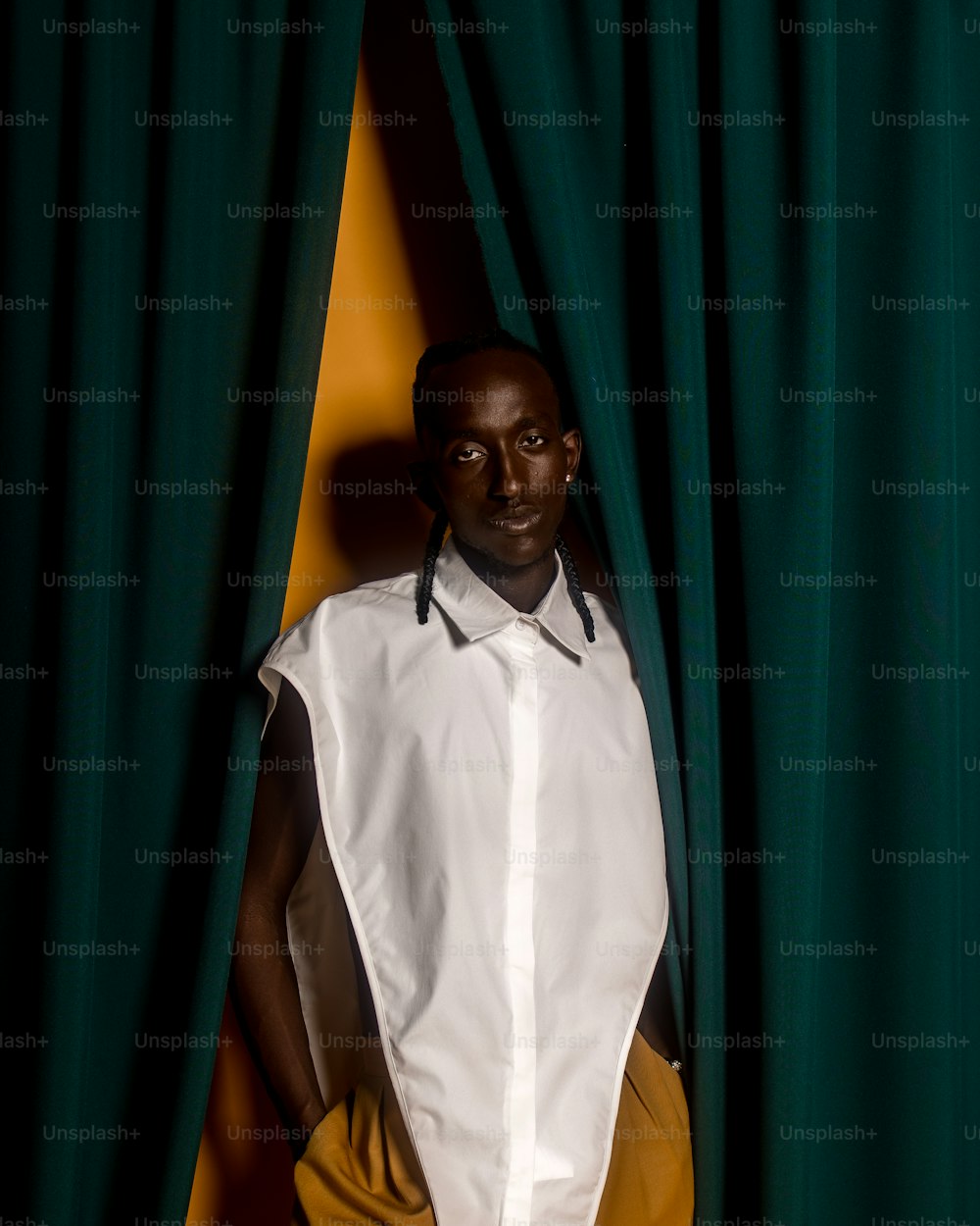 a man standing behind a green curtain with his hands on his hips