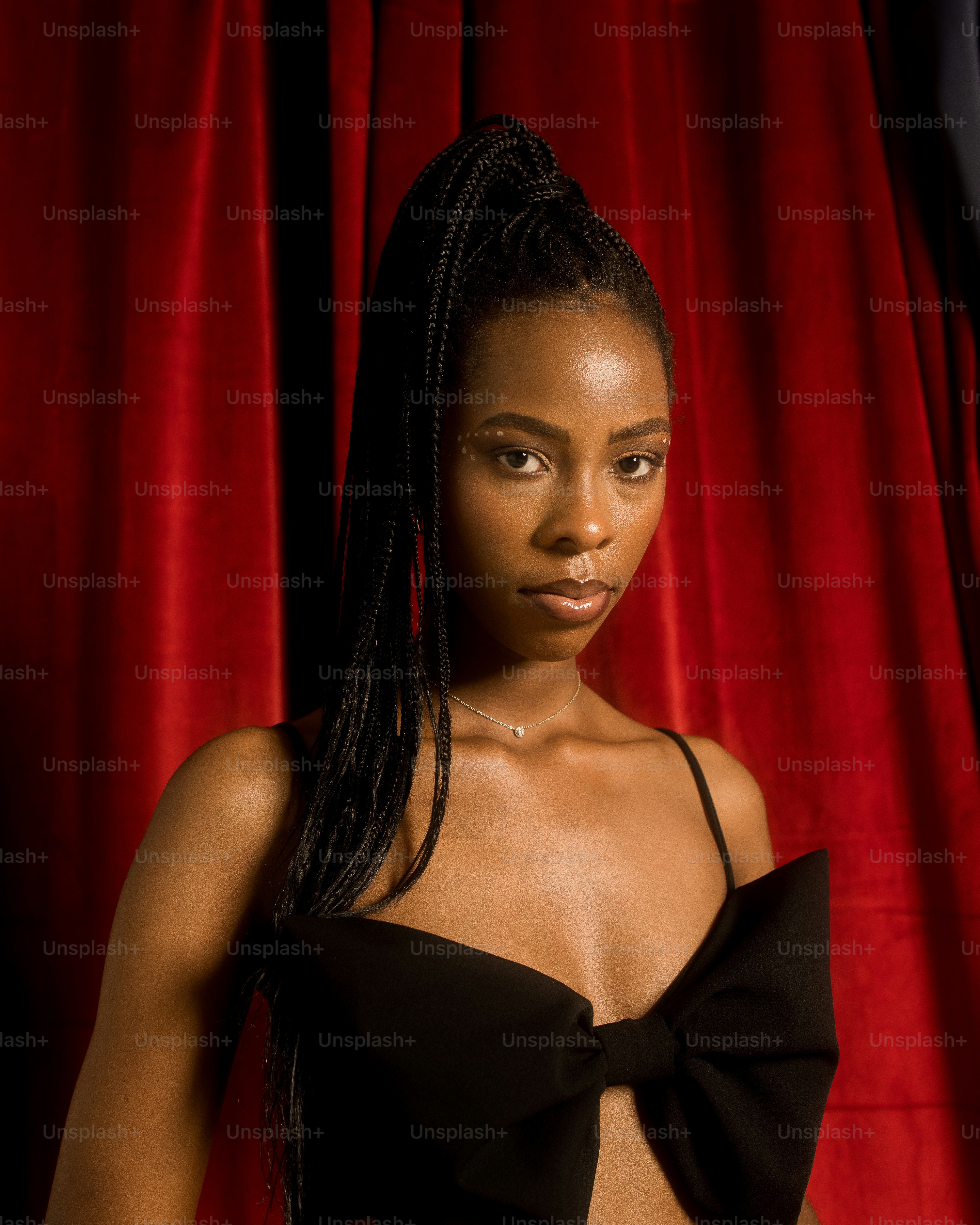 a woman in a black dress standing in front of a red curtain