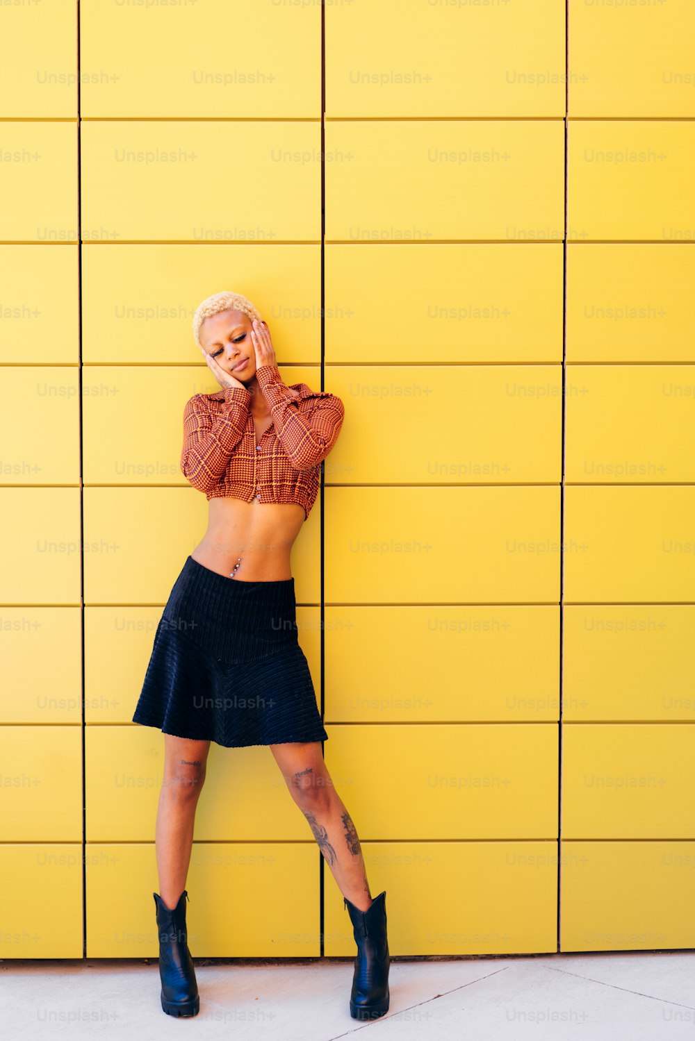 a woman leaning against a yellow wall talking on a cell phone