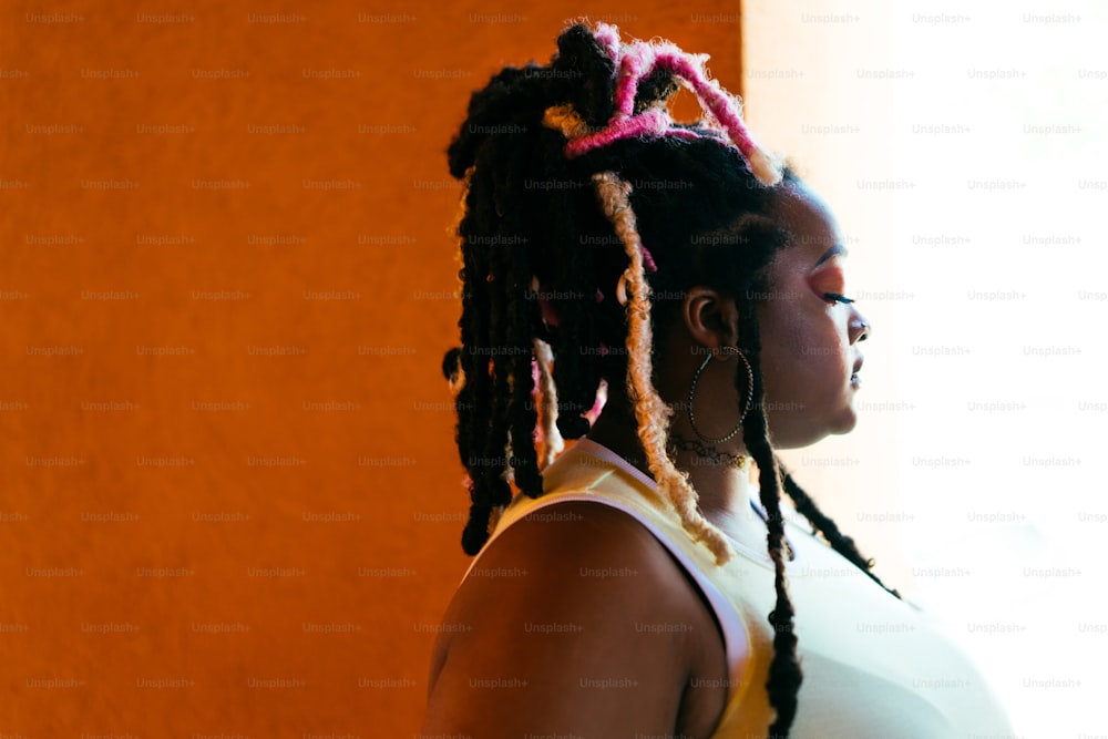 a woman with dreadlocks standing in front of a window
