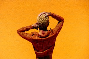 a woman with her hands on her head standing in front of a yellow wall