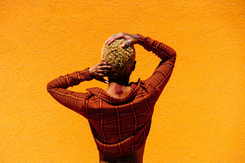 a woman with her hands on her head standing in front of a yellow wall