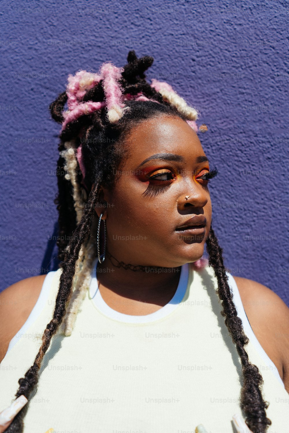 a woman with dreadlocks standing in front of a purple wall