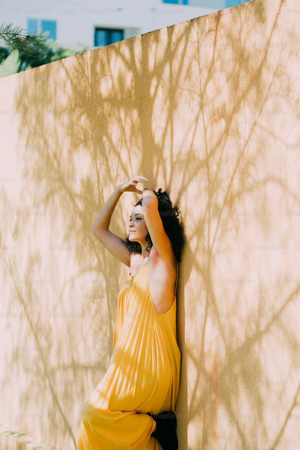 a woman in a yellow dress leaning against a wall