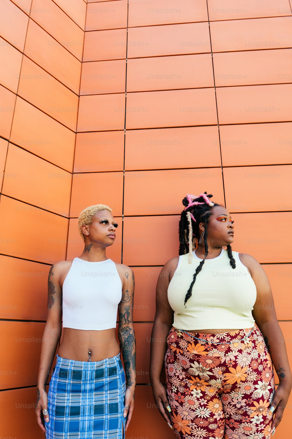 two women standing next to each other in front of a wall
