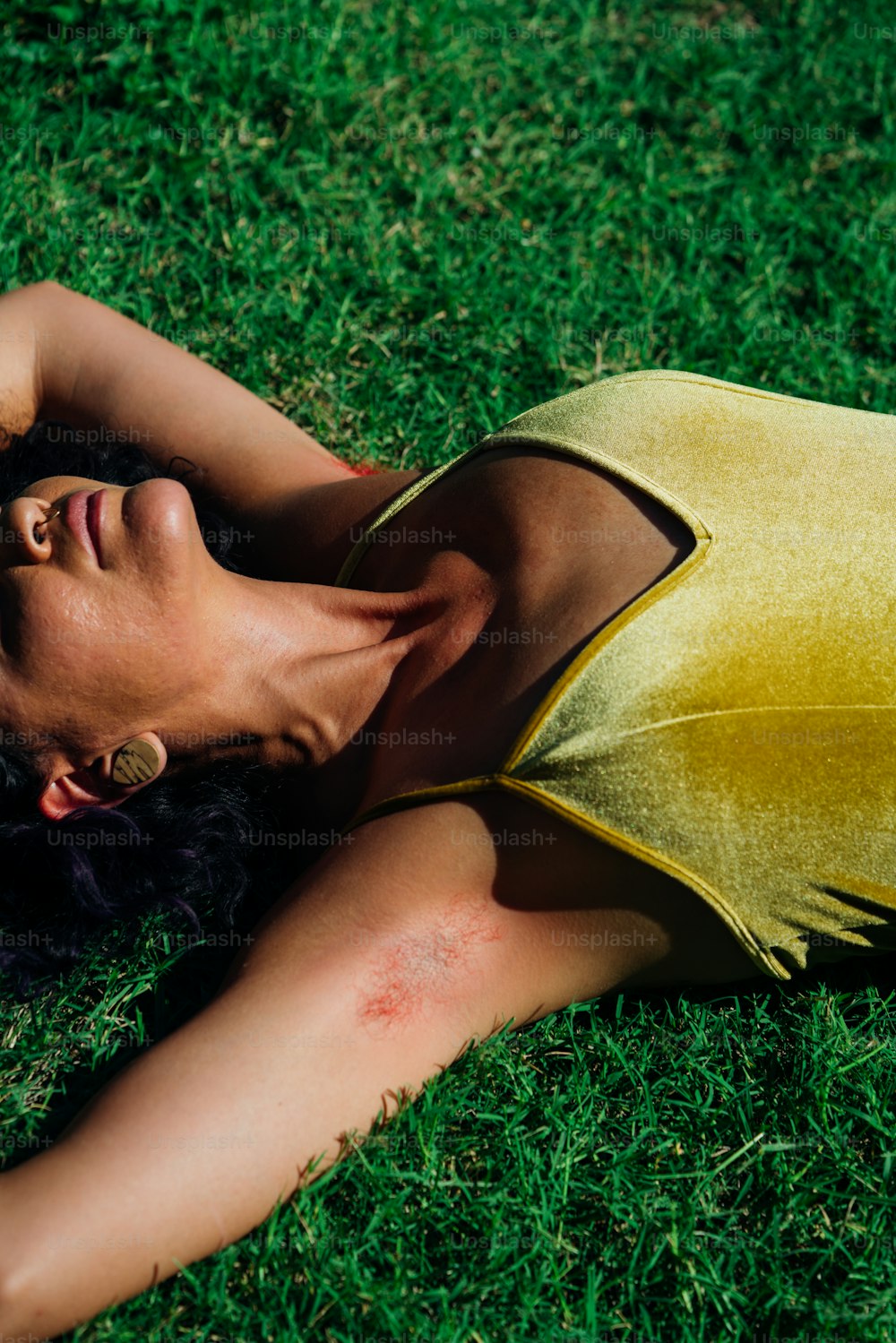 uma mulher deitada na grama de olhos fechados
