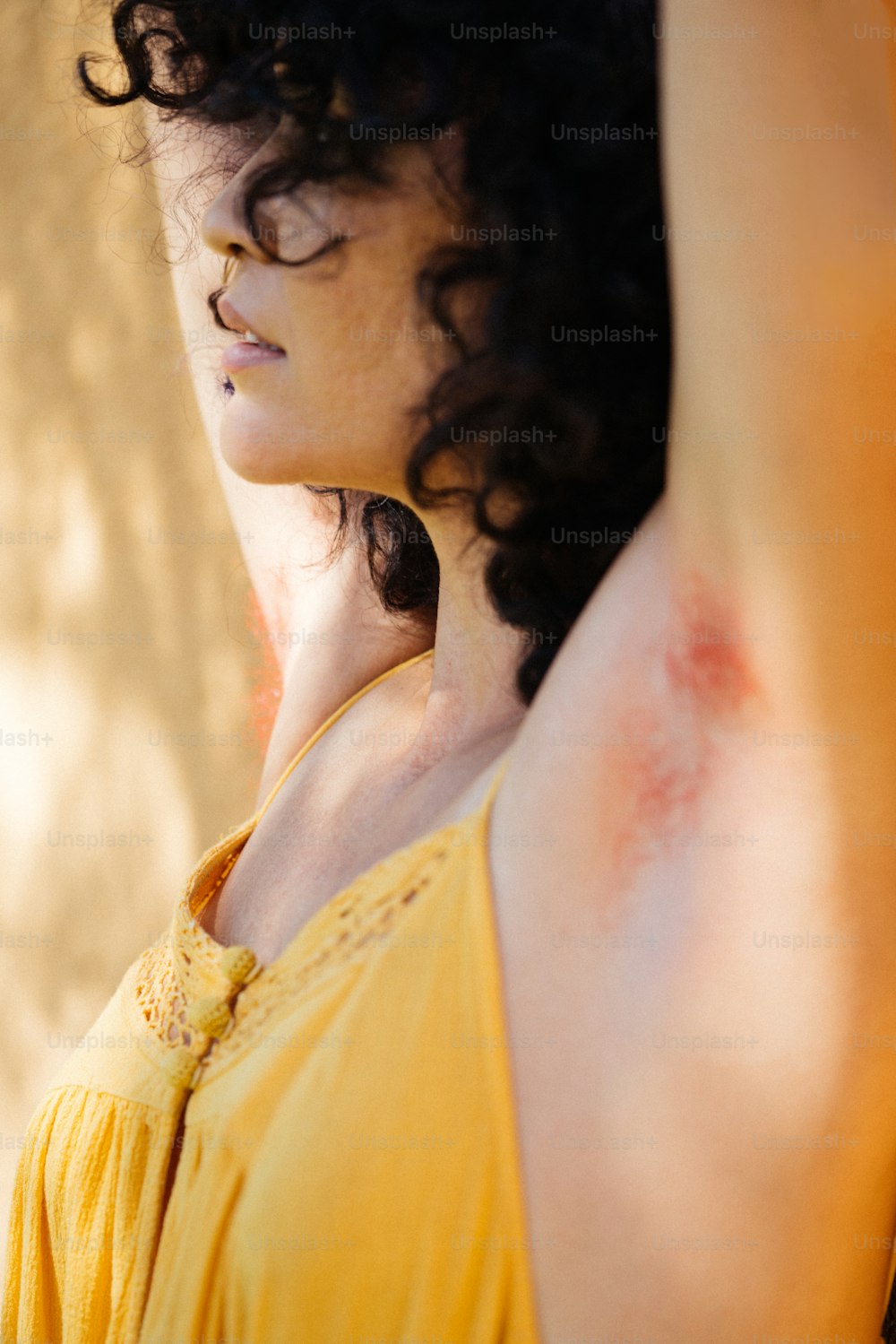 a woman in a yellow dress holding her arm up