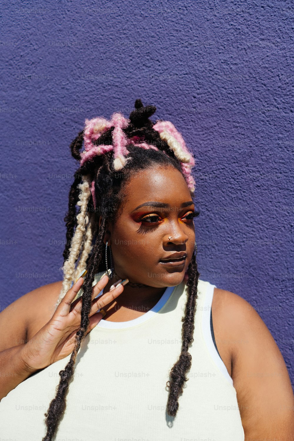 a woman with dreadlocks standing in front of a purple wall