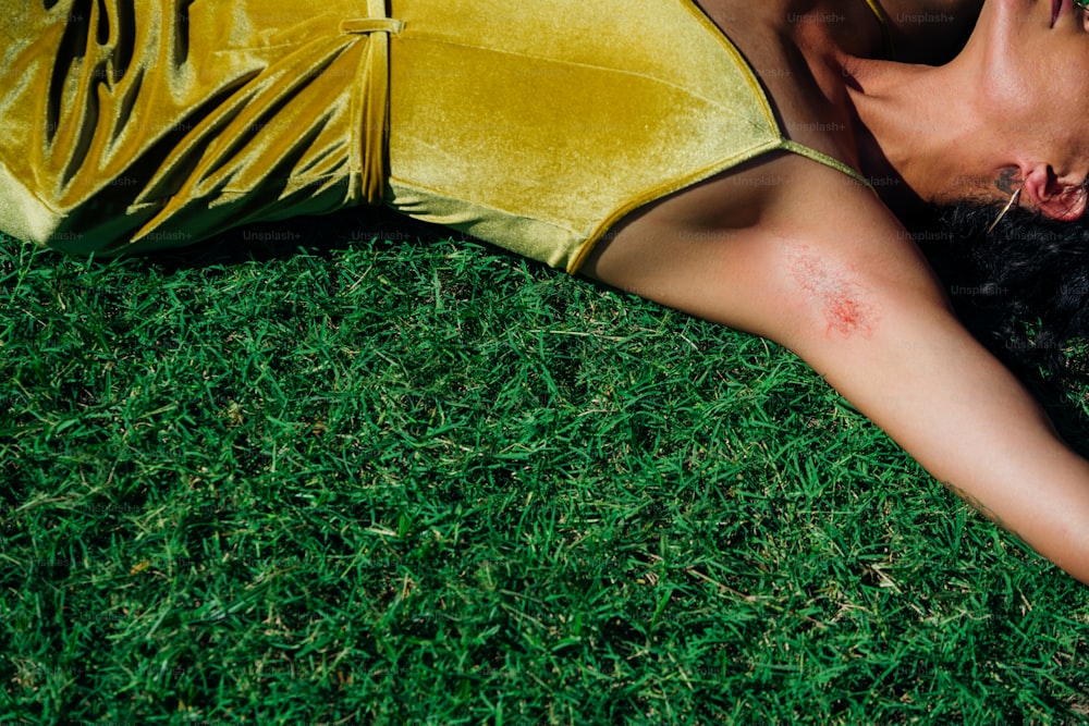 a woman in a yellow dress laying on the grass
