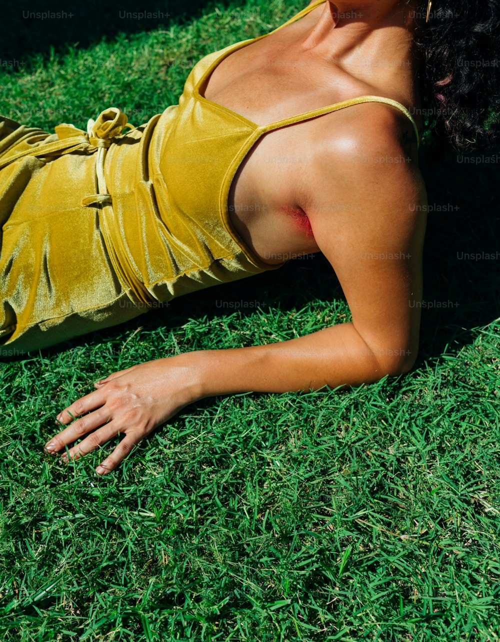 Eine Frau in einem gelben Kleid liegt im Gras